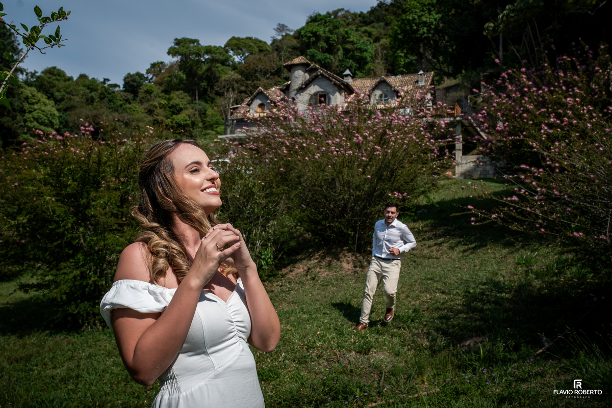Ivanna e Luis Gustavo entre flores com o Castelo de Pedra ao fundo durante ensaio em Itamonte