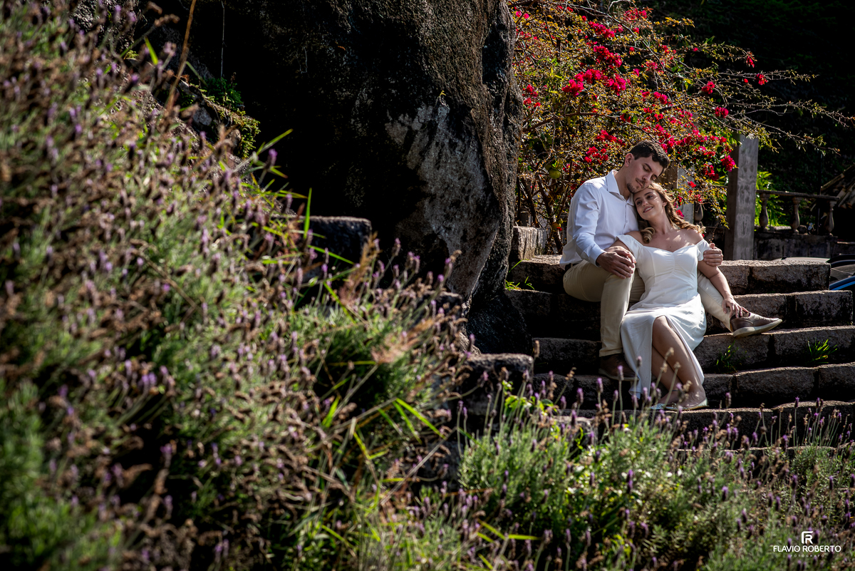 Casal abraçado entre flores e pedras durante ensaio Pre Wedding no Castelo de Pedra