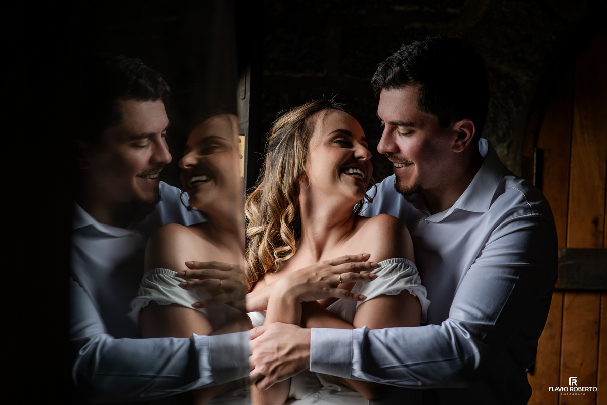 Ivanna e Luis Gustavo sorrindo em retrato com reflexos no interior do Castelo de Pedra em Itamonte