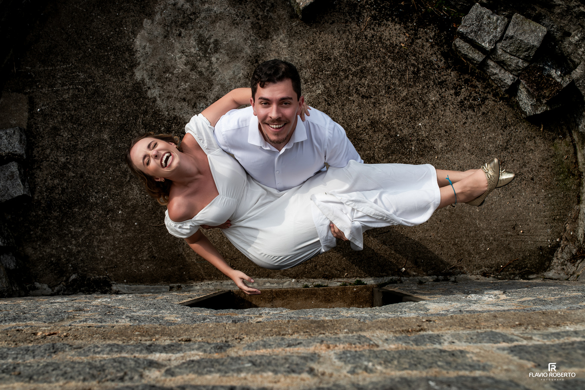 Casal sorrindo fotografado de cima durante ensaio pré-wedding no Castelo de Pedra, em Itamonte, sul de Minas Gerais.