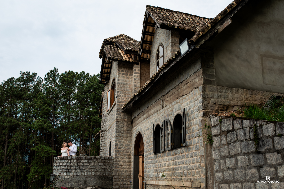 Casal fotografado diante da arquitetura rústica do Castelo de Pedra durante ensaio pré-wedding em Itamonte MG.