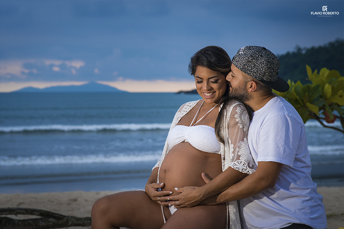 Casal Gestante sentado na areia conversando na frente do mar. Ensaio de Gestante em Ubatuba.