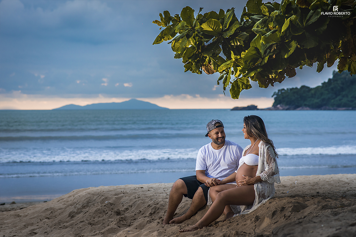 Casal Gestante sentado na areia conversando na frente do mar. Ensaio de Gestante em Ubatuba.
