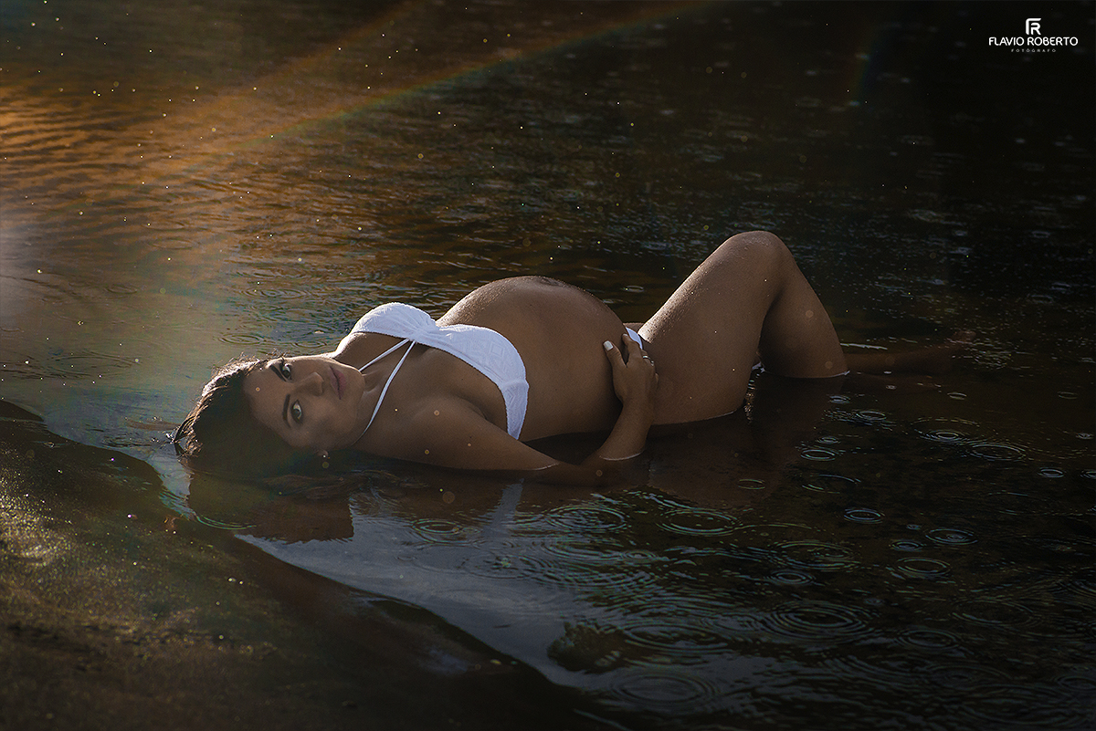 Gestante deitada na praia mostrando sua barriga durante o Ensaio de Gestante em Ubatuba.