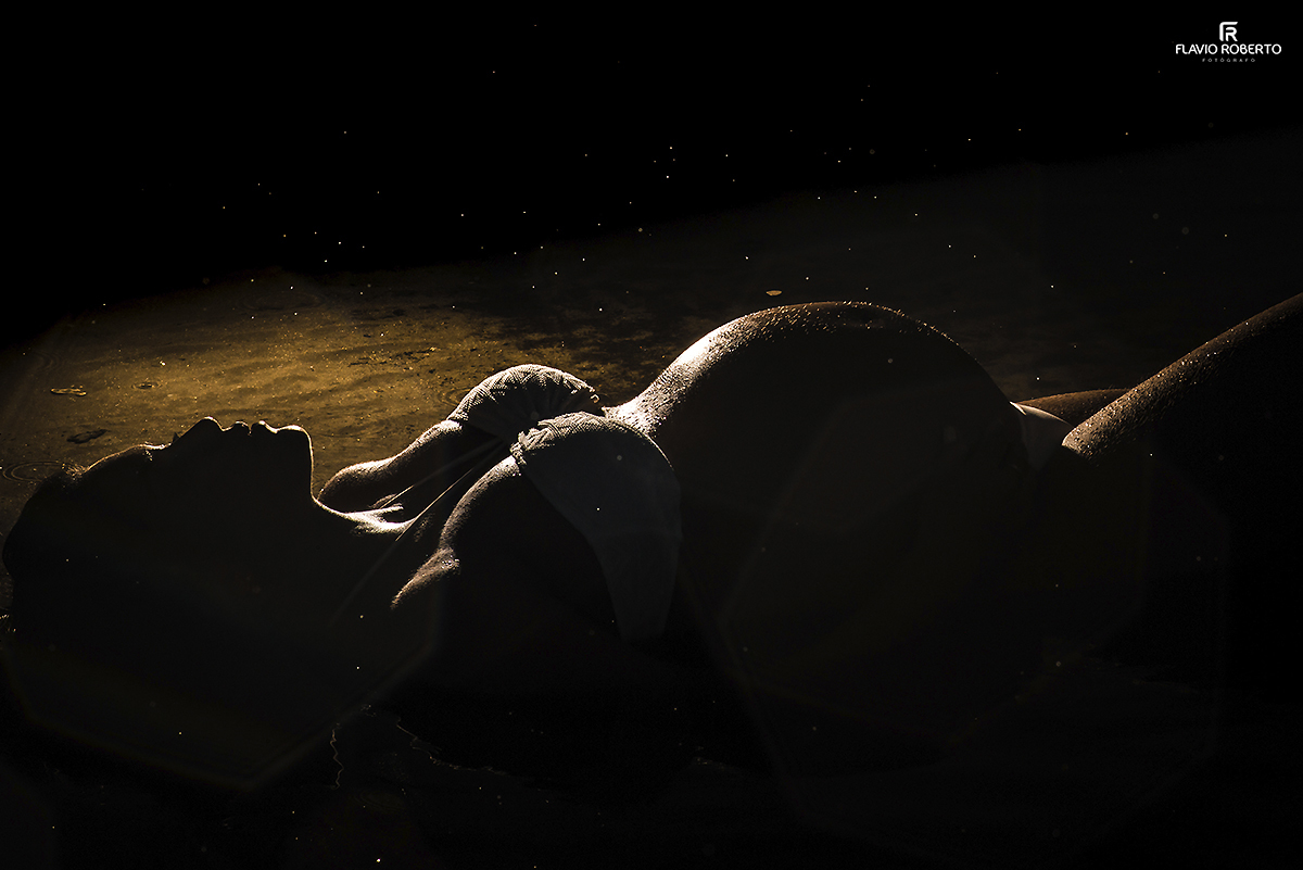 Gestante deitada na praia mostrando sua barriga durante o Ensaio de Gestante em Ubatuba.