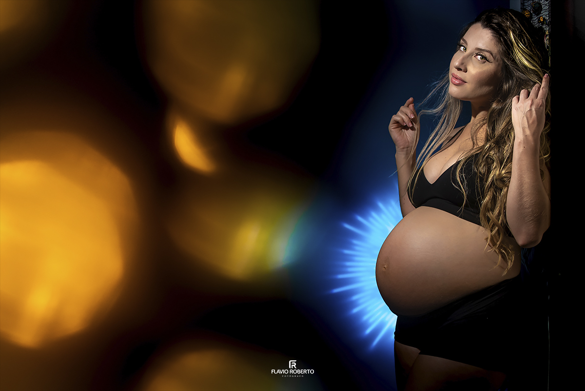 Gestante toda iluminada por um jogo de luzes coloridos. Foto artística de Gestante. Ensaio de Gestante em Ubatuba.