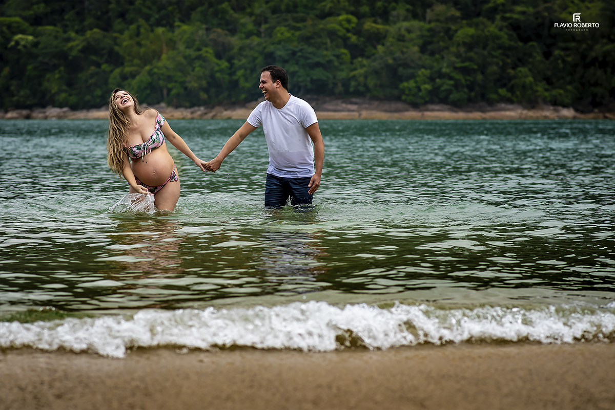 gestante caminhando na praia com seu esposo durante o Ensaio de Gestante em Ubatuba