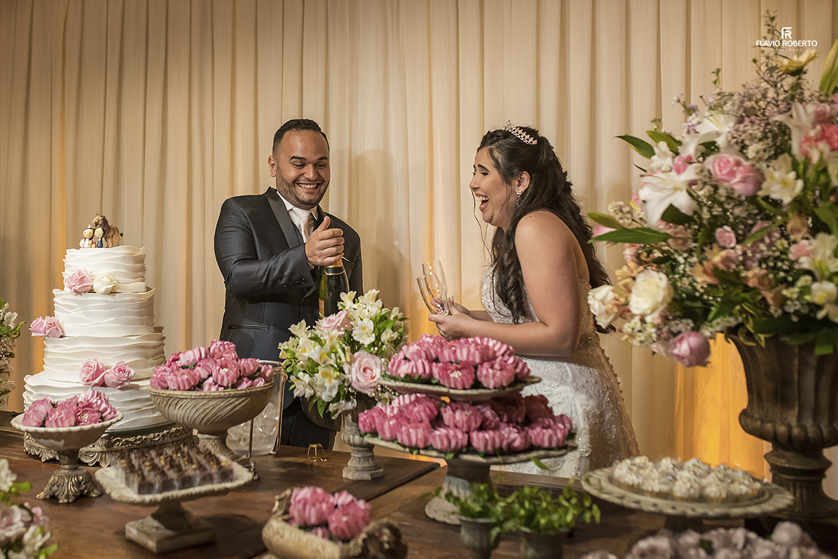 noivos estourando a champagne na mesa do bolo