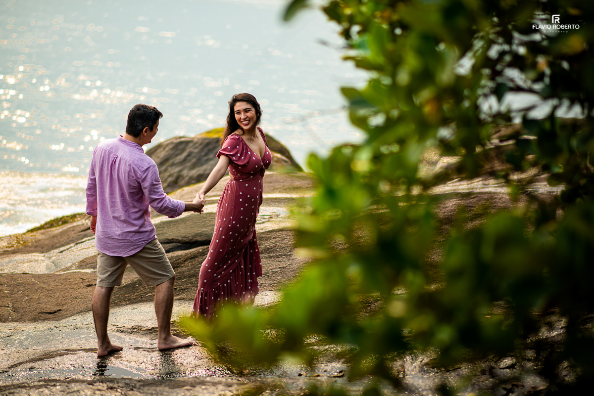 Namorados caminhado nas pedras com vista para o mar.
