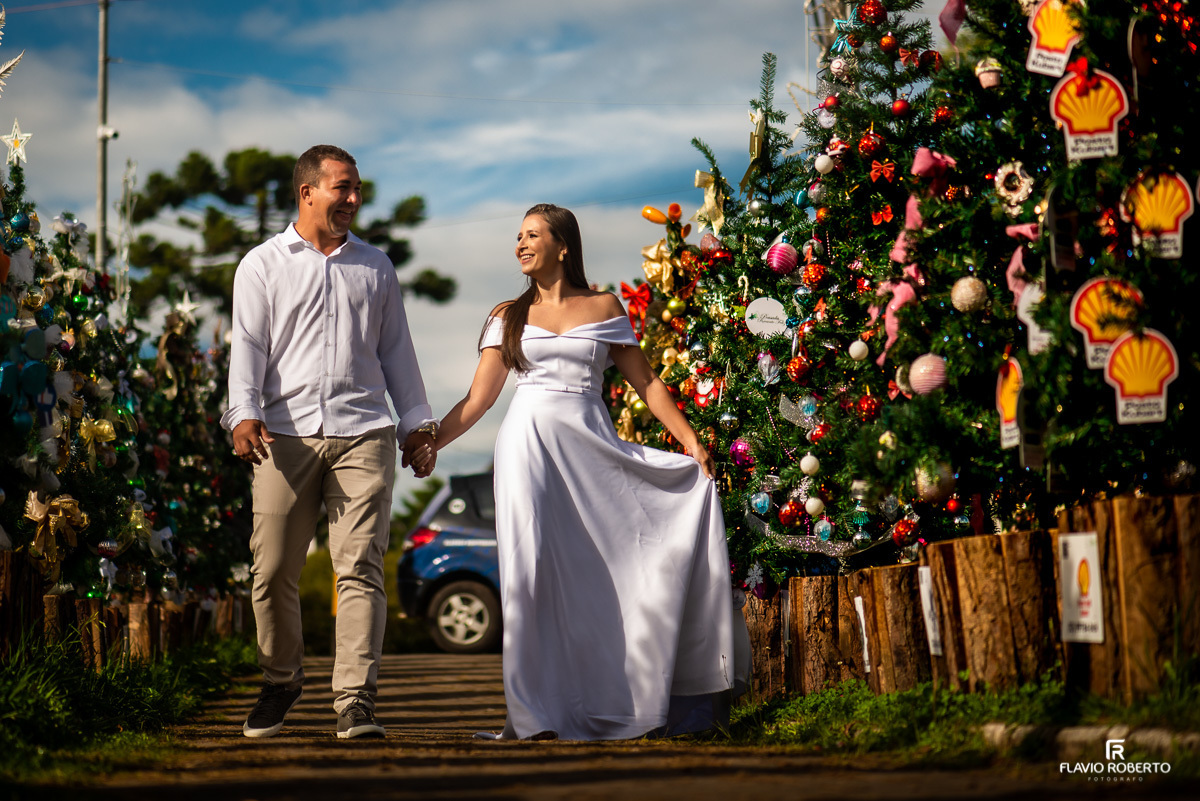 Casal se caminhando entre árvores de Natal durante Ensaio Fotográfico em Campos do Jordão 