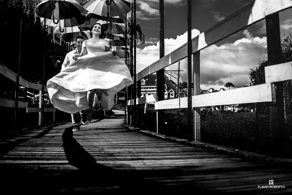 noivos correndo pela ponte das sombrinhas durante Ensaio de Casal em Campos do Jordão 