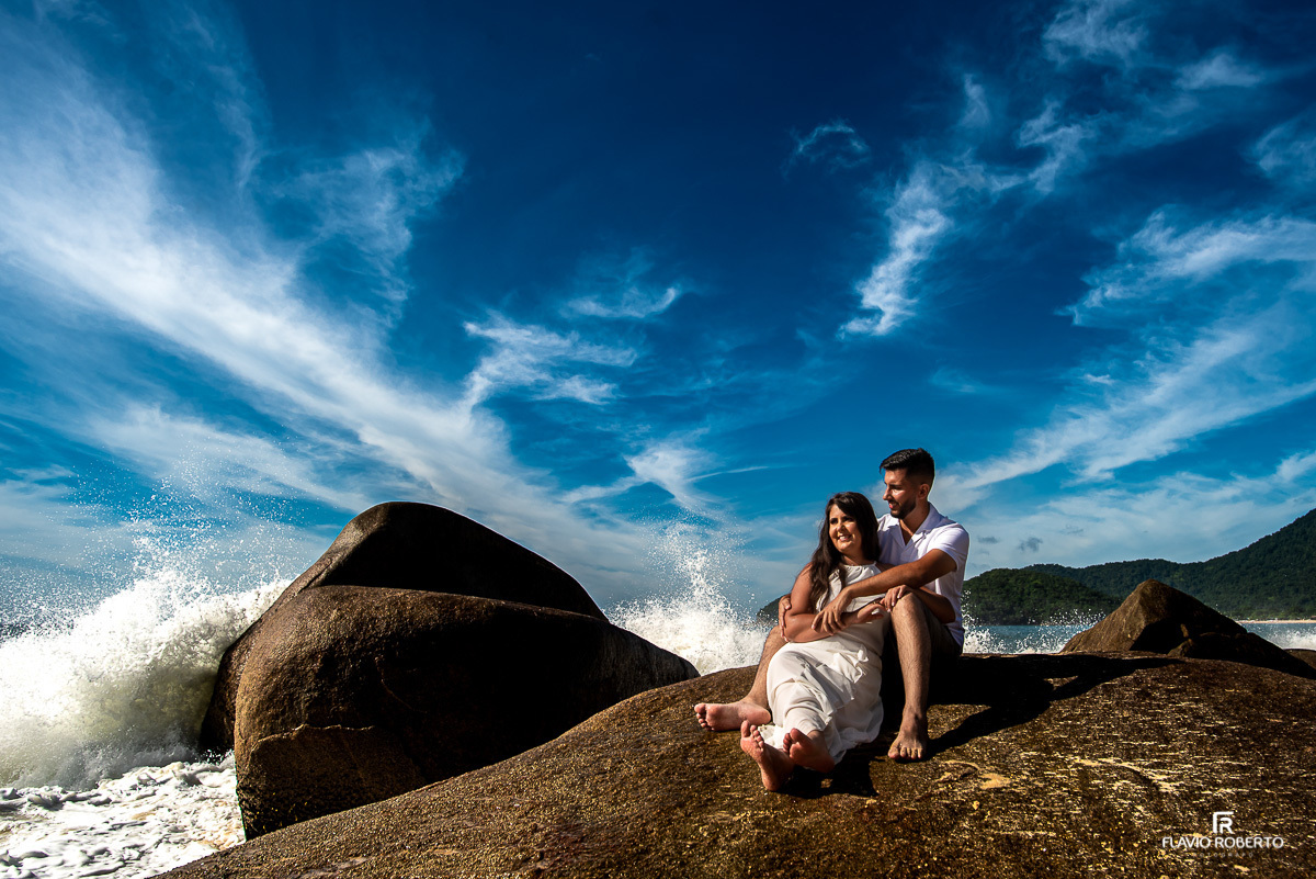 casal de namorados sentado na pedra observando o mar