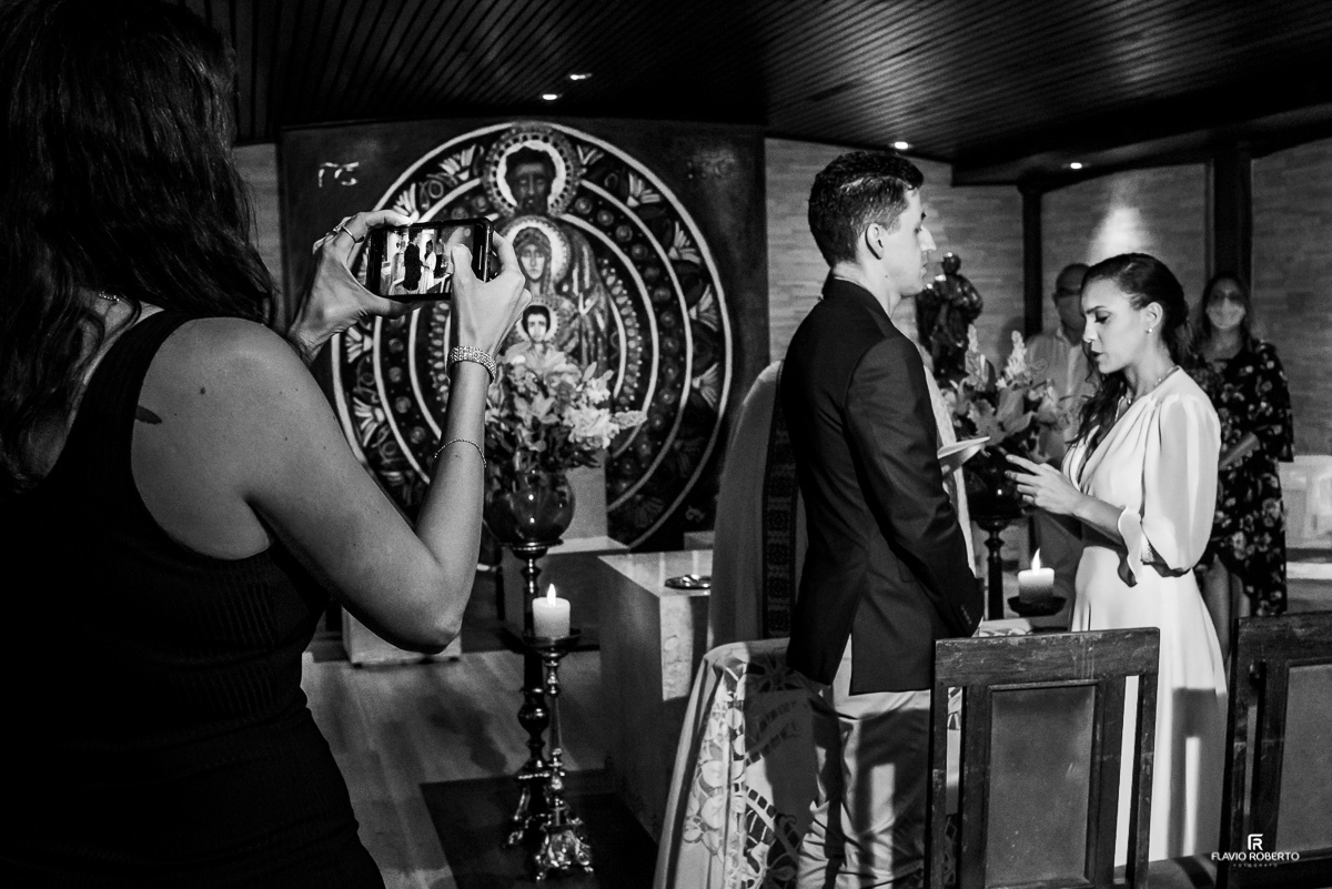 madrinha fazendo foto com o celular dos noivos trocando aliança em sp