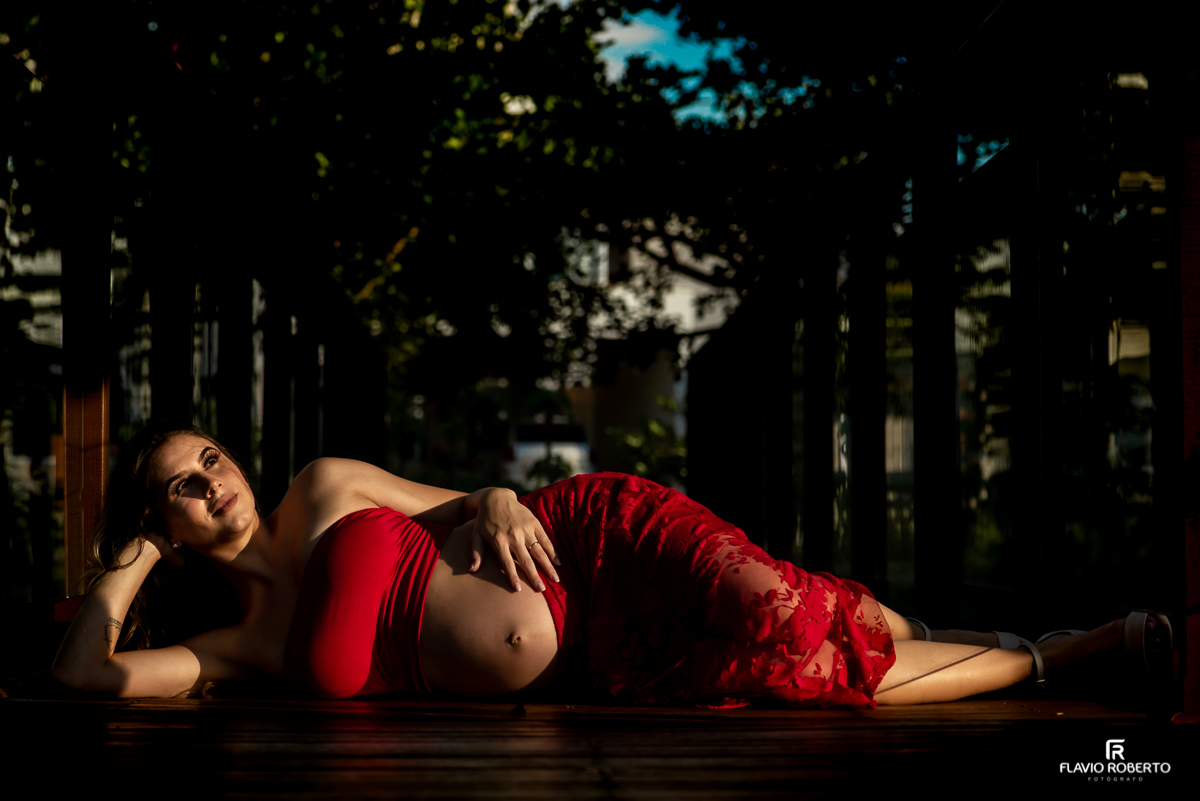 Gestante deitada numa pontinha de madeira durante ensaio de gestante em Taubaté.