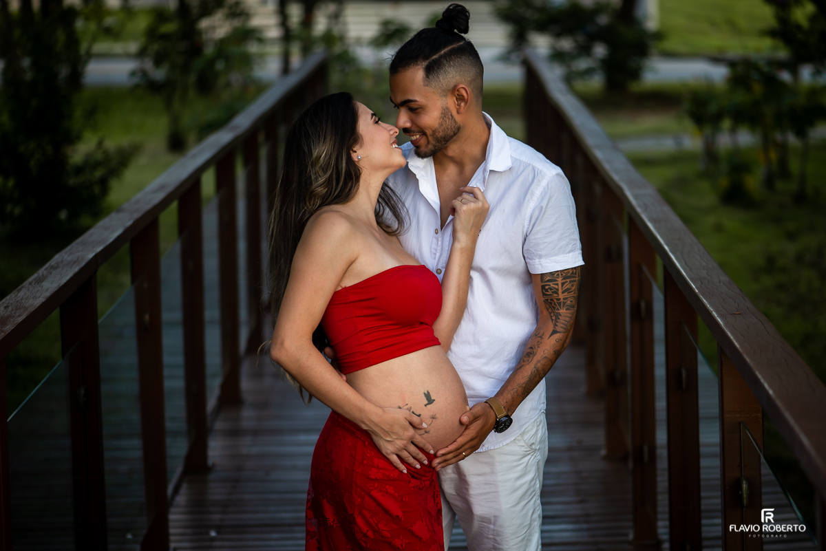 Casal de gestante abraçados numa pontinha de madeira durante ensaio de gestante em Taubaté.