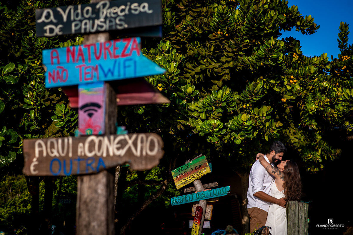 Casal namorando do lado de umas plaquinhas coloridas em praia de Ubatuba