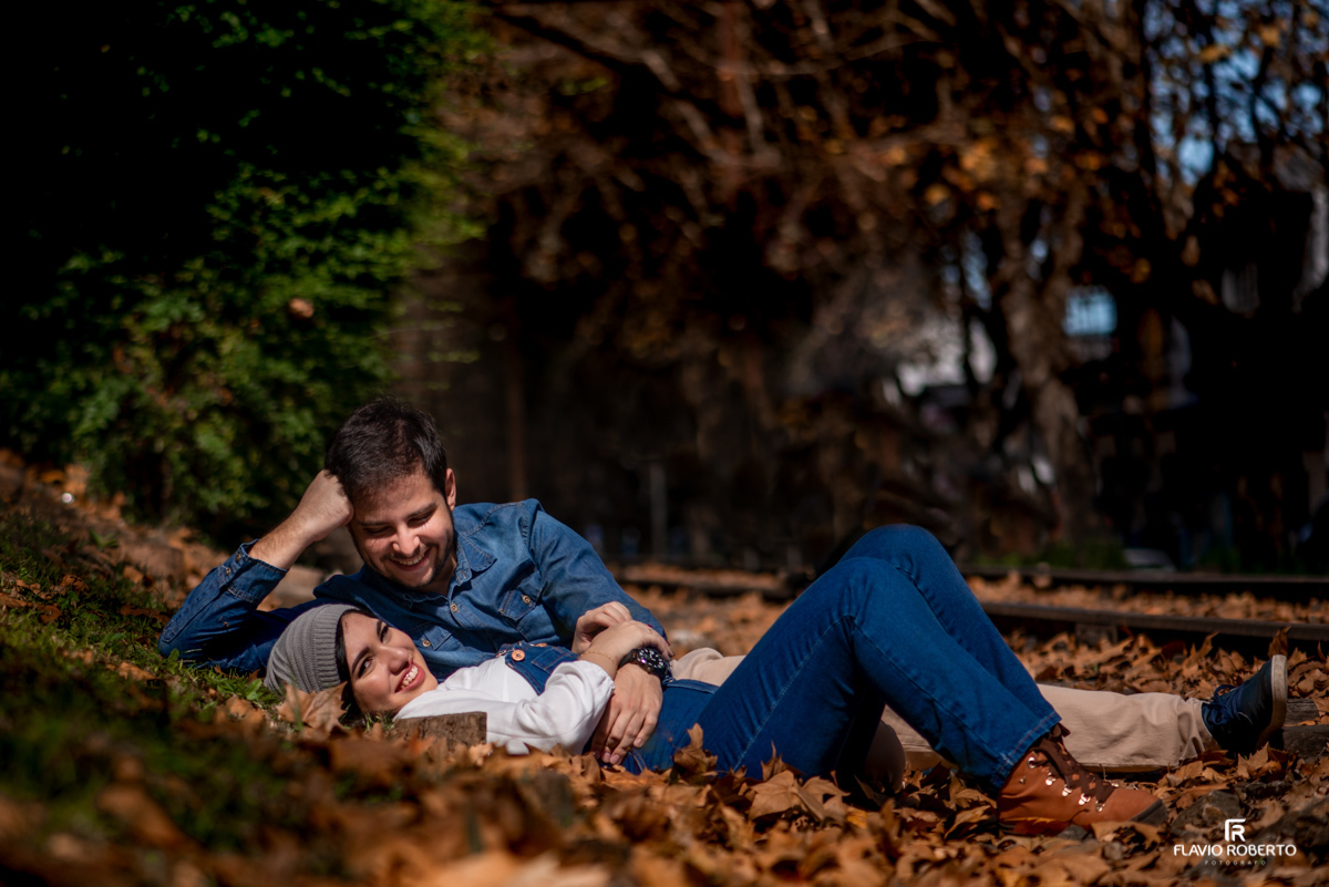 Casal deitado do lado da linha de trem entre as folhas secas do outono de Campos do Jordão no Ensaio Pré Wedding.