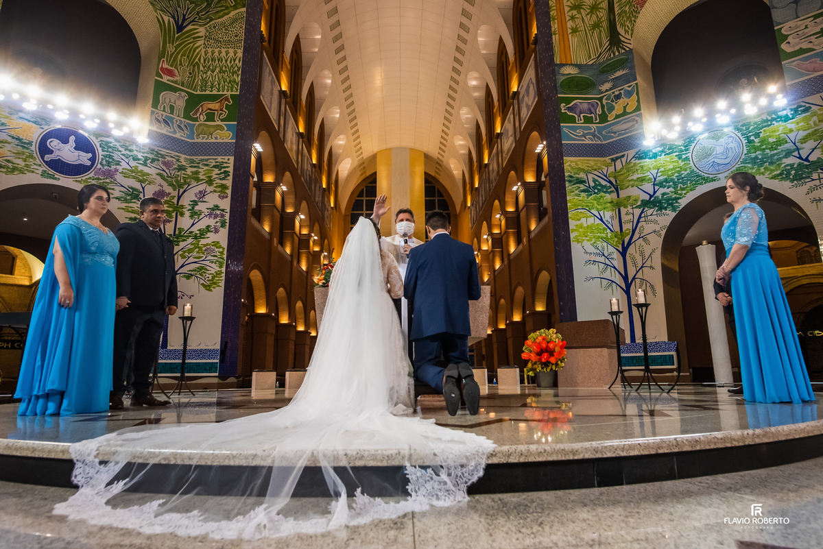 Noivos ajoelhados recebendo a bênção do sacerdote durante casamento no Santuário Nacional de Aparecida