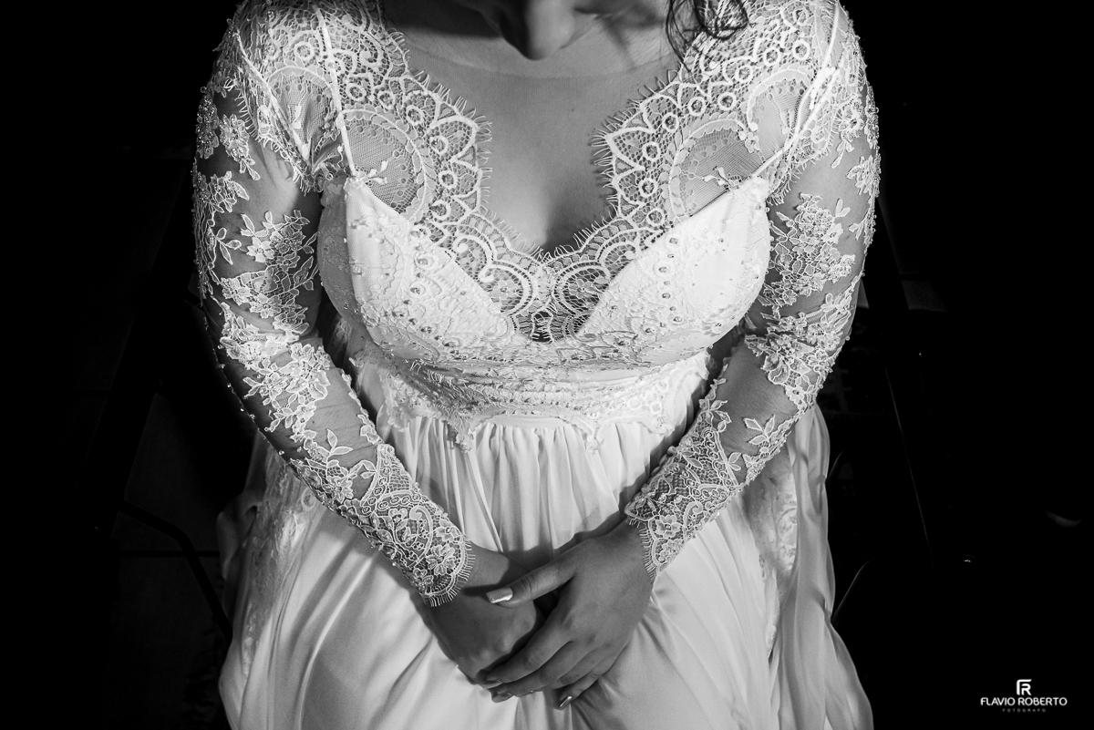 Noiva sentada mostrando os detalhes do decote de seu vestido.