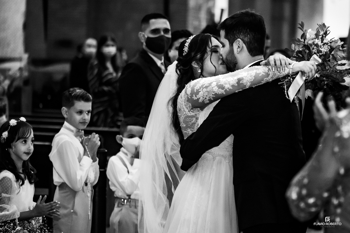 Noivos se beijando com as crianças olhando durante Casamento no Santuário Nacional de Aparecida-SP.