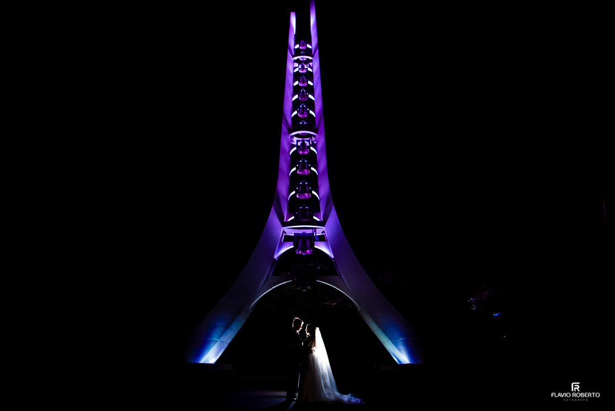 Casal de esposos abraçados em baixo do Campanário do Santuário Nacional de Aparecida em SP.