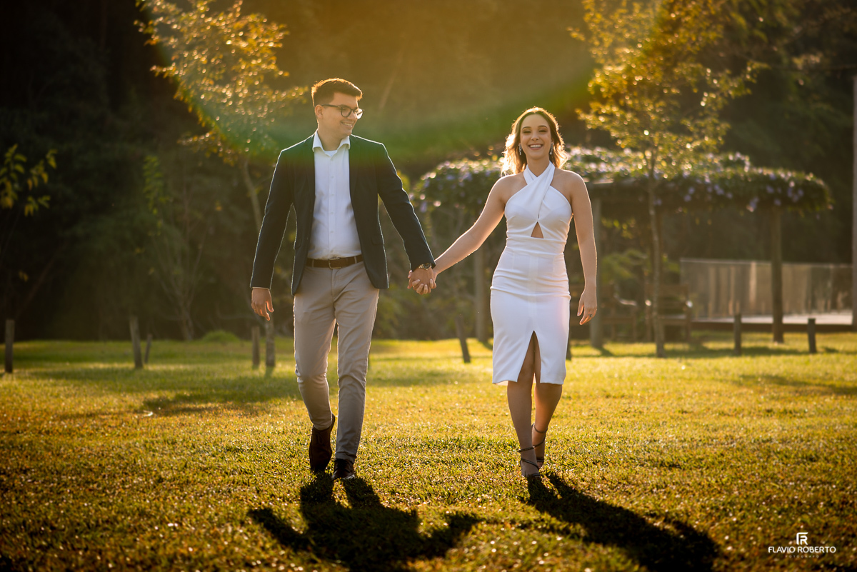 Noivos caminhando de mãos dadas durante amanhecer no Recanto do Bosque em Guaratinguetá.