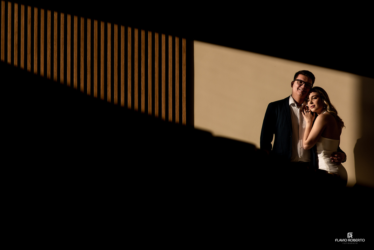 Casal abraçado encostado na parede da Capela do Recanto do Bosque em Guaratinguetá.