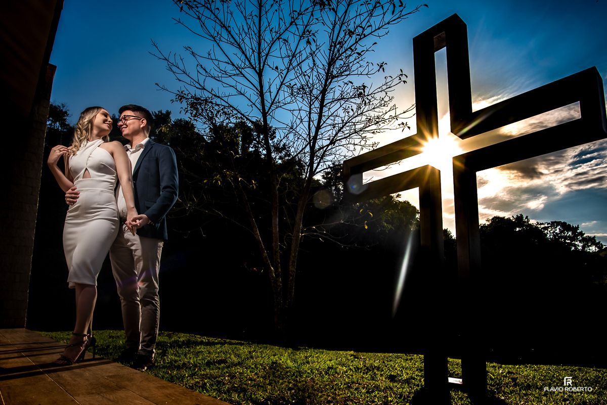 Noivos abraçados ao lado da cruz da Capela do Restaurante Recanto do Bosque em Guaratinguetá.