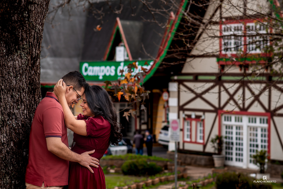 Noivos abraçados no pórtico de Campos do Jordão durante Ensaio de Casal celebrando Bodas de Madeira 