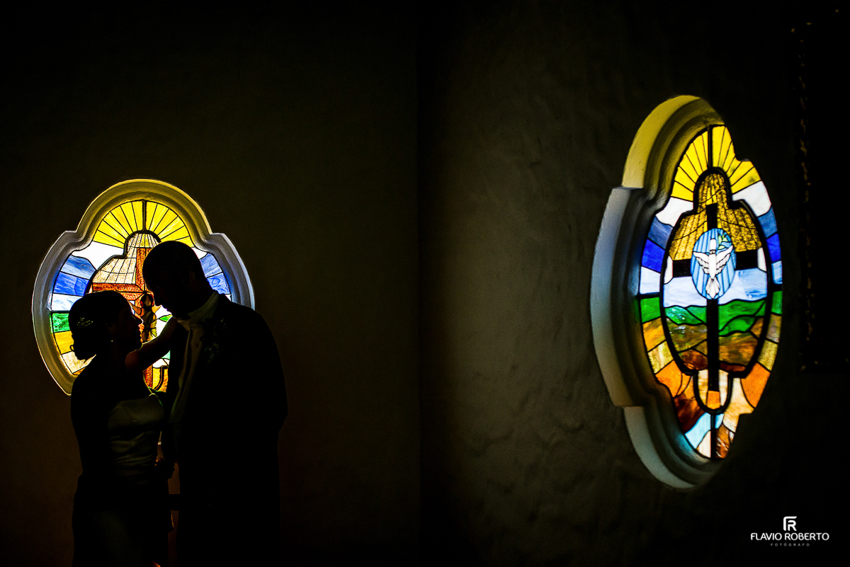 silueta dos noivos se beijando em frente os vitrais da Igreja