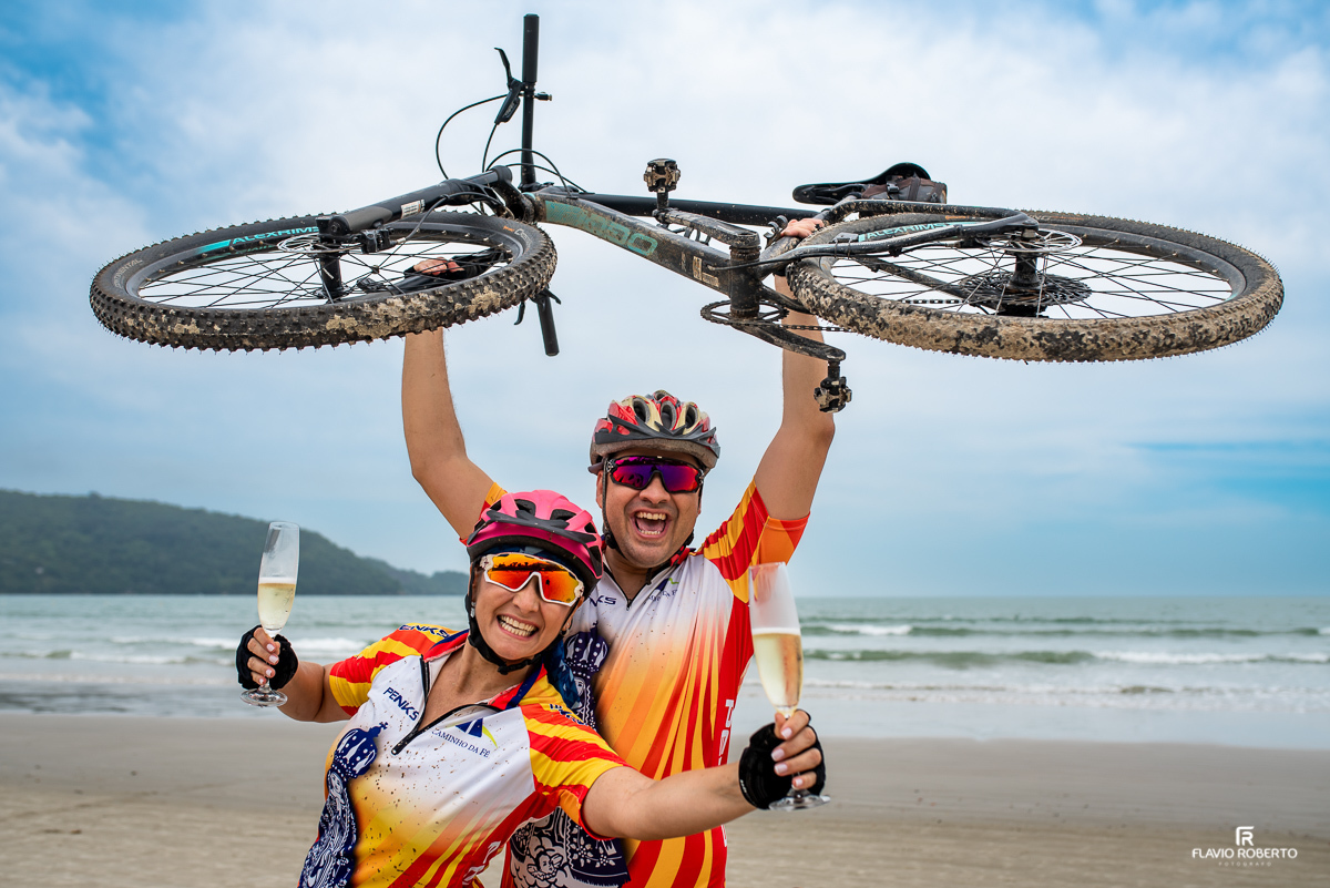 Casal de noivos ciclistas brindando com espumante na praia da Lagoinha em Ubatuba durante Ensaio Pre Wedding
