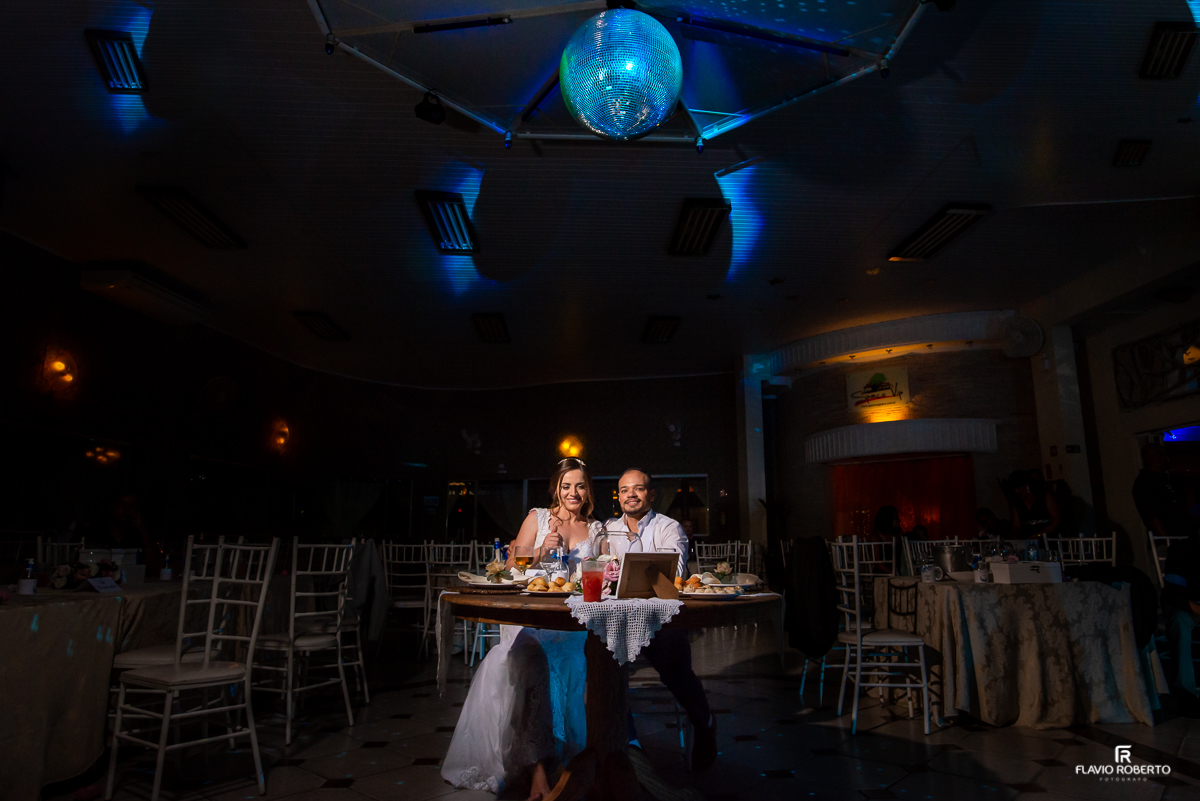 Noivos sentados na mesa no final da festa em casamento no Espaço Vip de Guaratingueta-SP