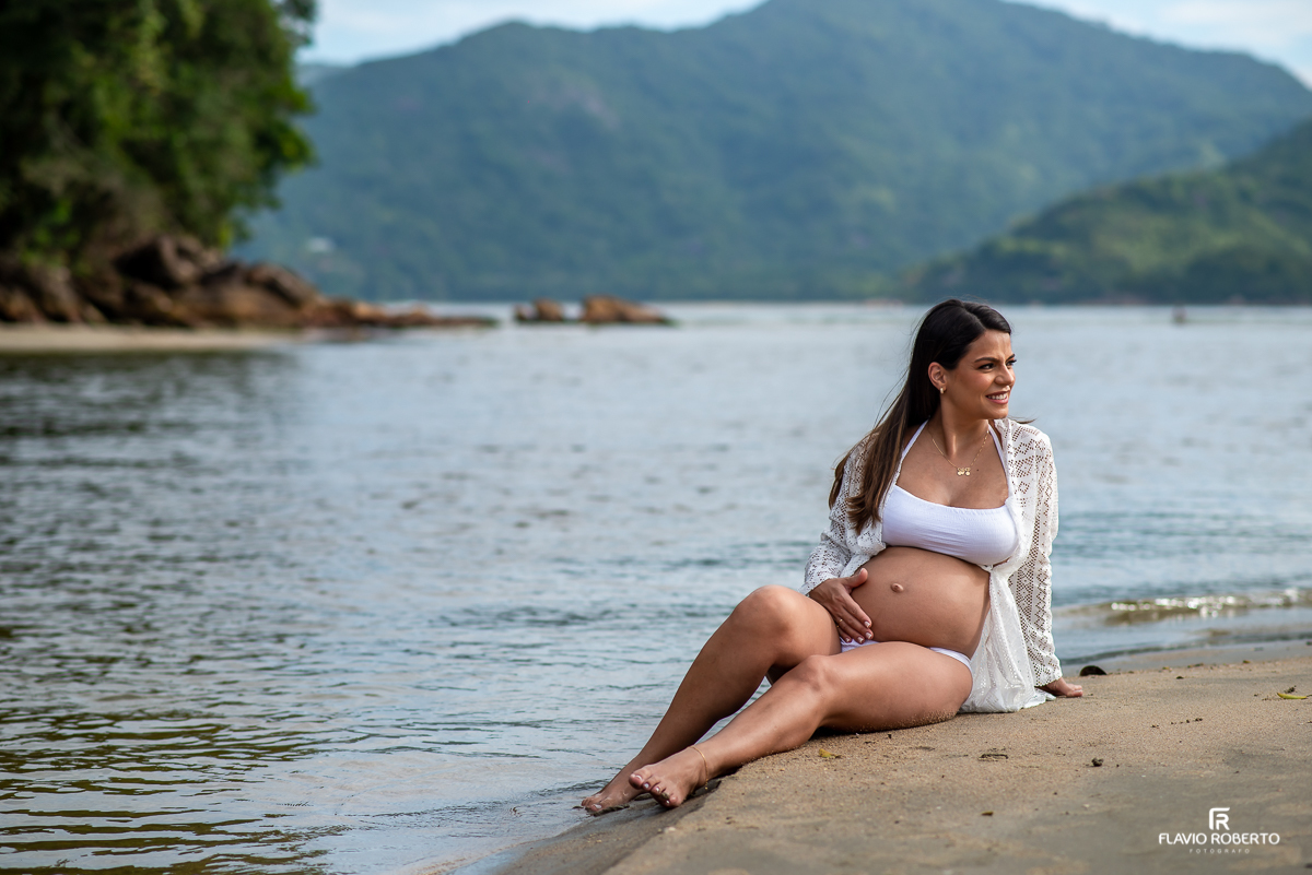 Gestante sentada na beira do mar durante ensaio de gestante na praia de Ubatuba 