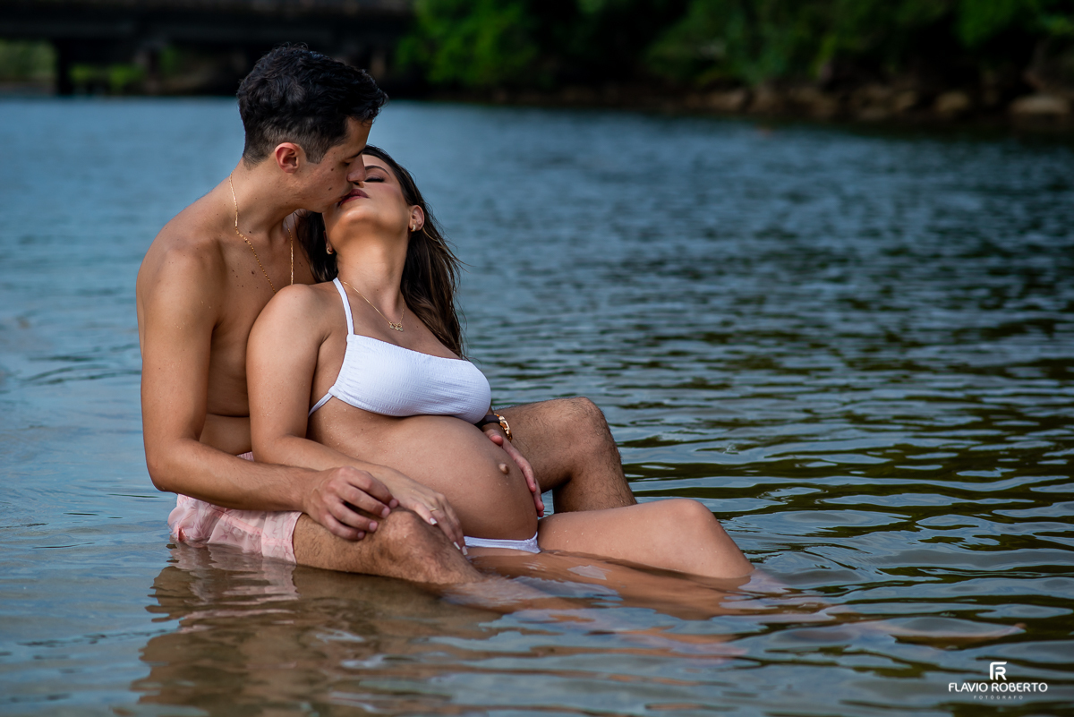 Gestante deitada com seu esposo na beira do rio durante ensaio de gestante na praia de Ubatuba 