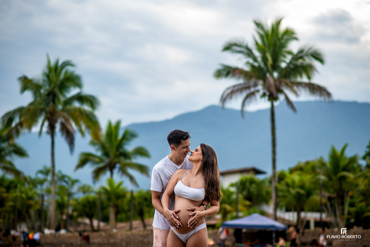 Gestante abraçada ao esposo durante ensaio na praia em Ubatuba