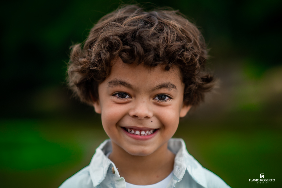 filho da gestante sorrindo durante ensaio de família na praia em Ubatuba