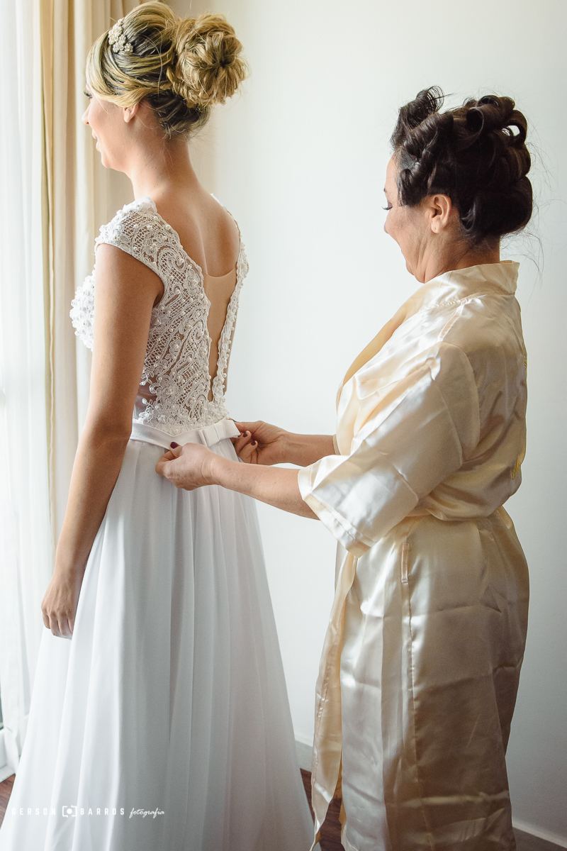 Mãe auxilia a noiva a vestir o lindo vestido em Macaé