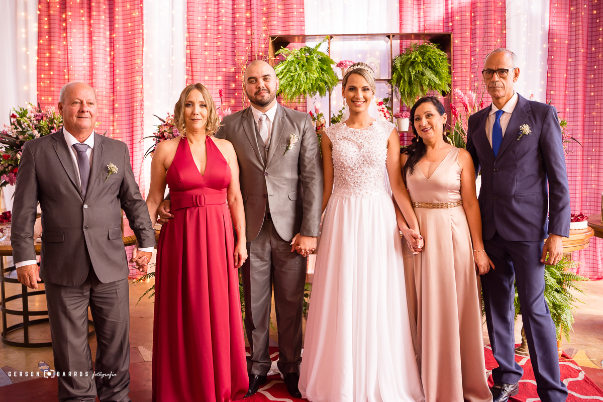 noivos radiantes com a familia posam para foto principal na mesa do bolo