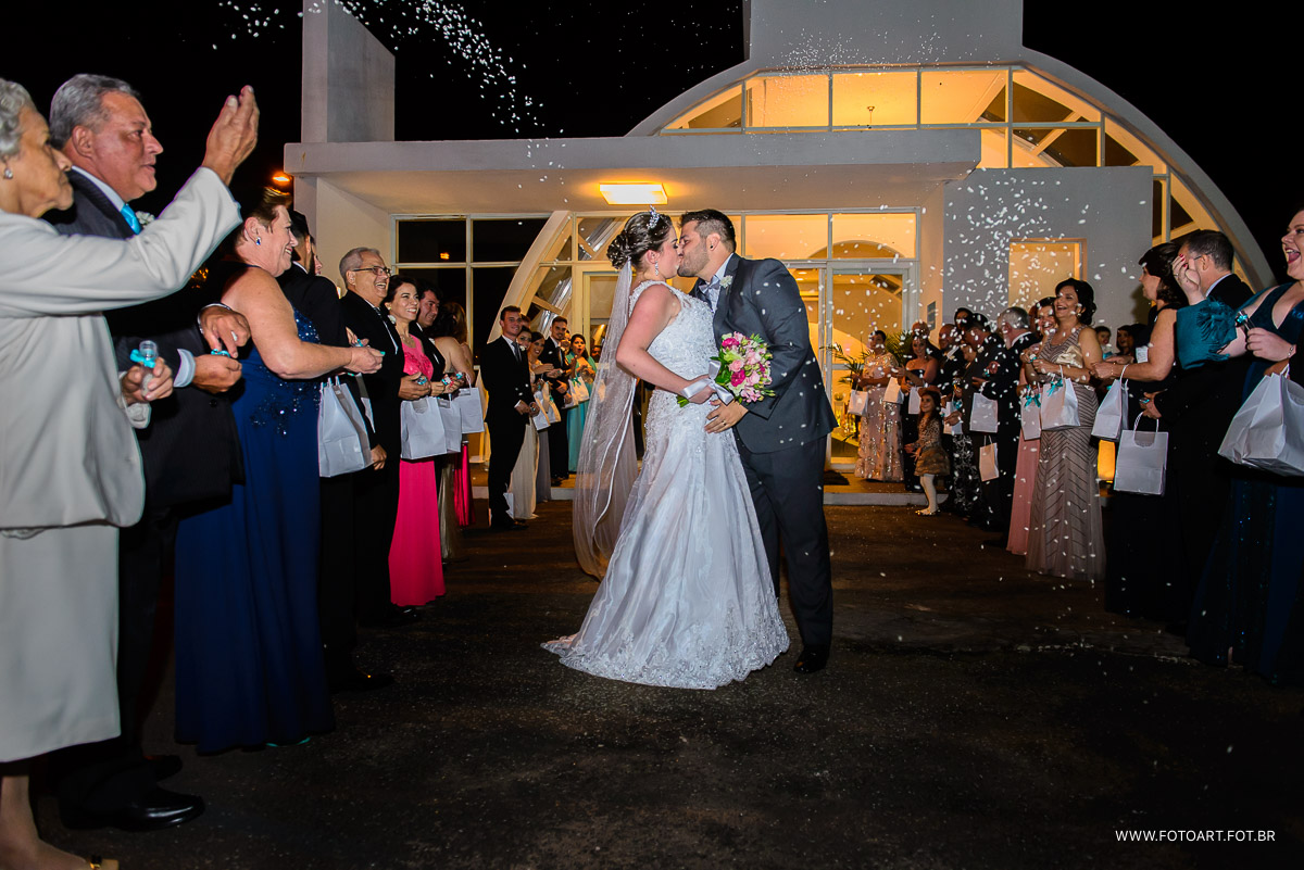 noivos se beijando e padrinhos jogando arroz