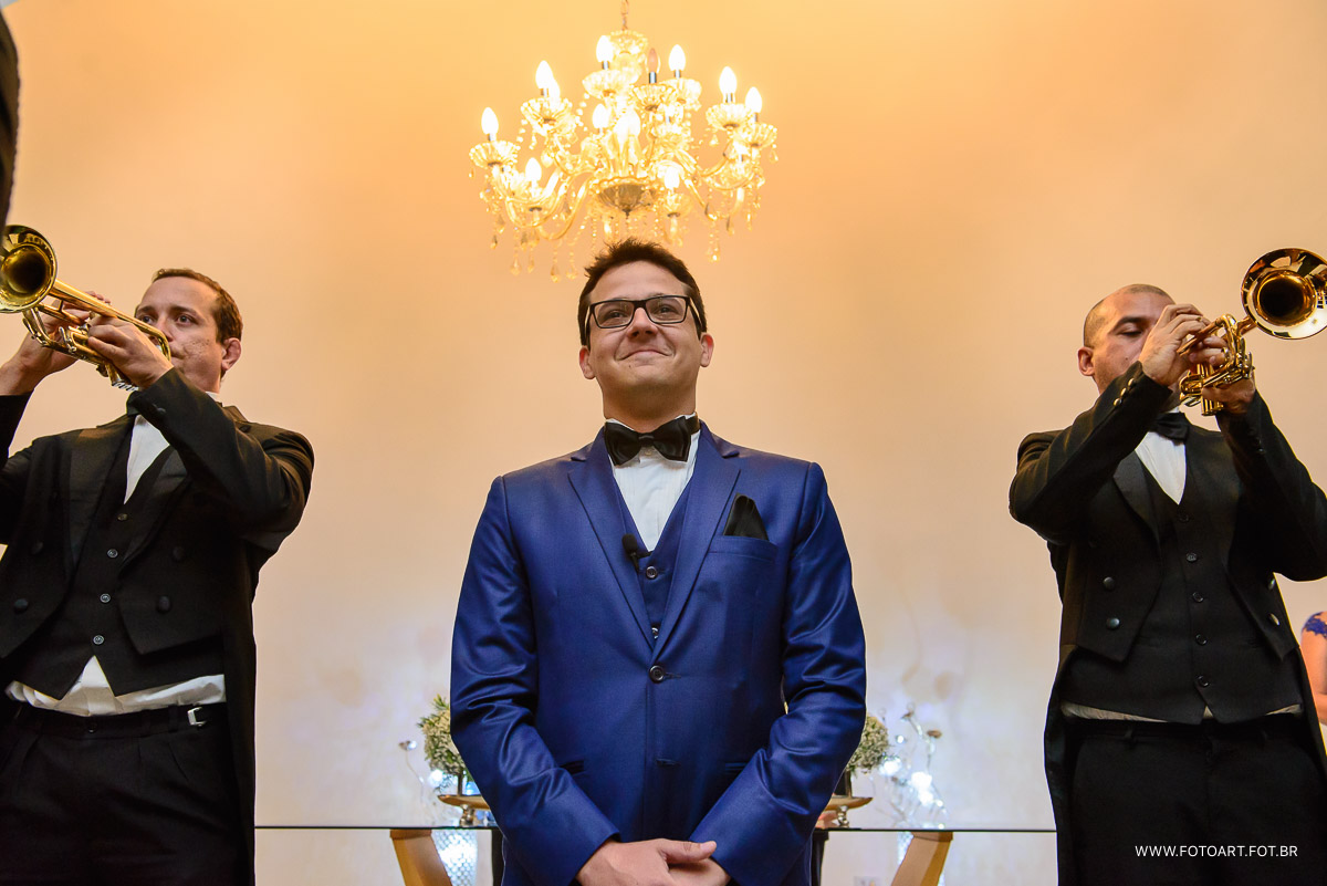 noivo esperando entrada da noiva ao fundo tritono bonacelli tocando tropetes  na  capela de vidro do luz tropical  foto de Anderson Silva Fotoart fotografo sp