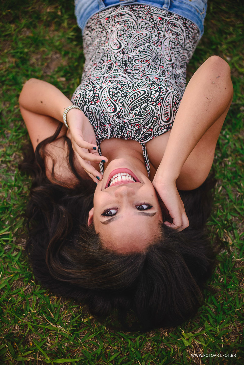 book de 15 anos com Mayra deitada na grama e sorrindo que aconteceu na unesp em Botucatu  foto de Anderson Silva Fotoart fotografo sp
