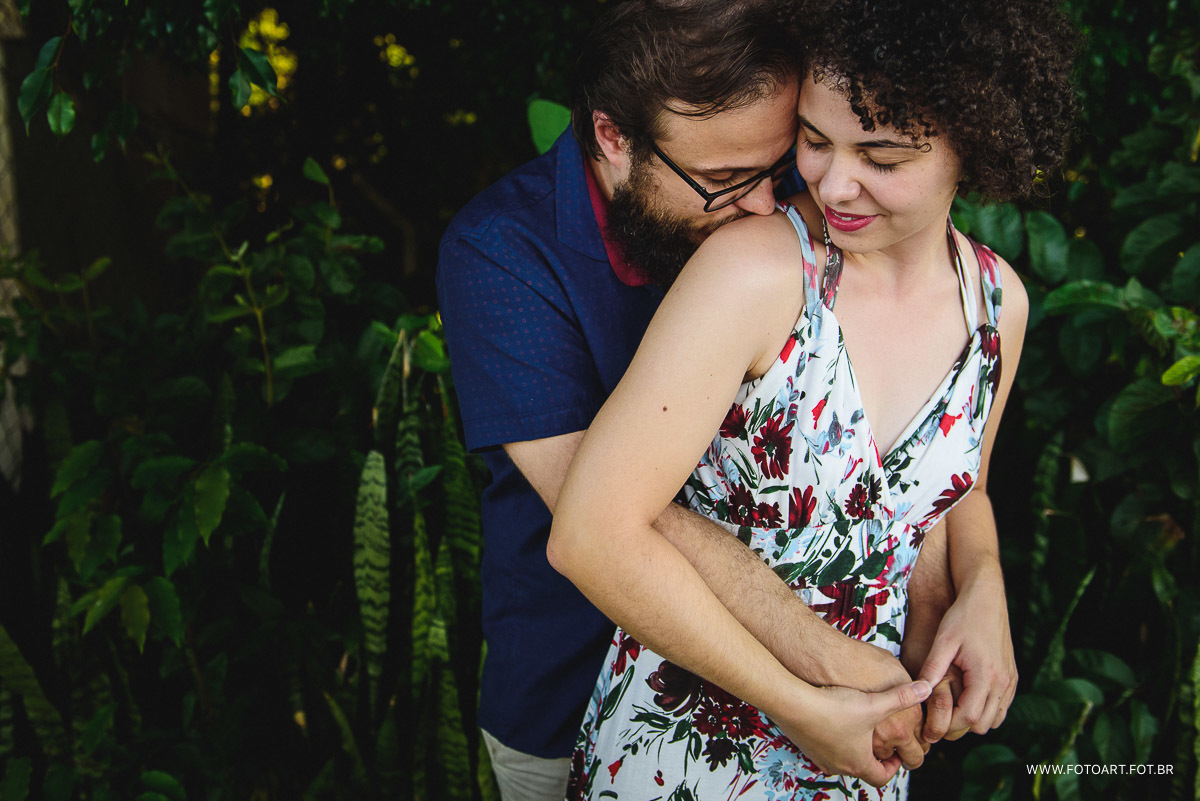 Noivo dando um abraco com beijinho no ombro de sua noiva com fundo verde de floresta na igrejinha de rubiao jr fotografo de casamento de Botucatu sao paulo e regiao Anderson Silva Fotoart