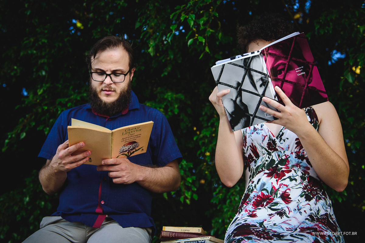 Amanda e Carlos fazendo leitura de um livro e ao fundo o verde de folhas de arvores fotografo de casamento de Botucatu sao paulo e regiao Anderson Silva Fotoart