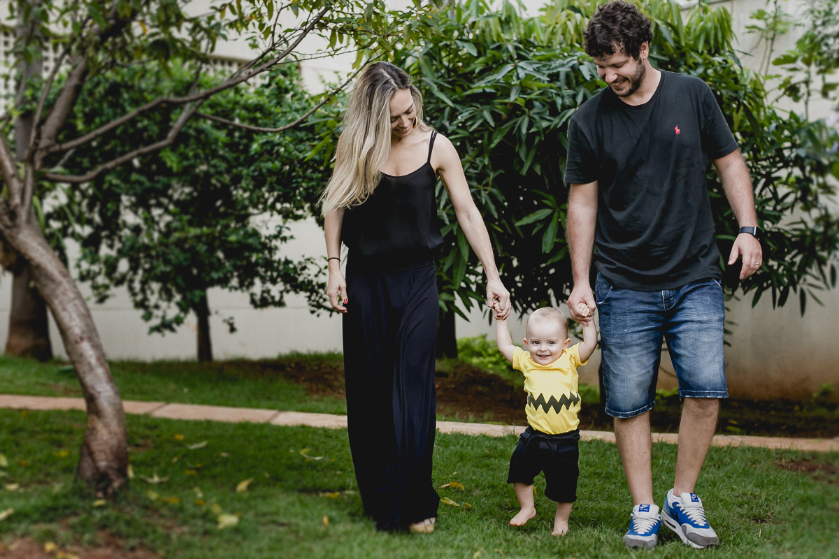 Joao caminhando com o papai e a mamae no ensaio familia