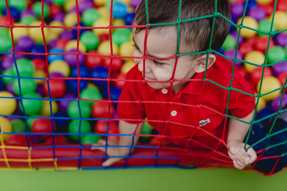 encostando o rosto na grade da piscina de bolinhas