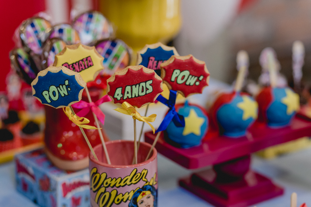 detalhes da mesa do bolo com o tema mulher maravilha e super heroinas