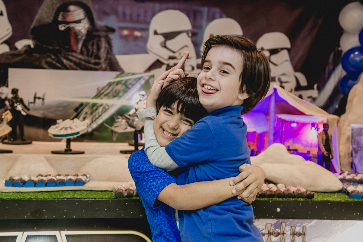 amigos se abraçando na frente da mesa do staw wars