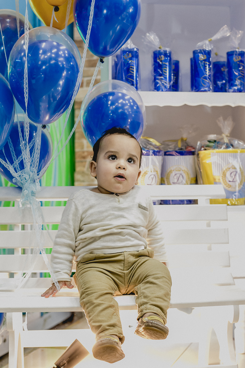 Davi sentado na cadeira na frente da mesa do bolo