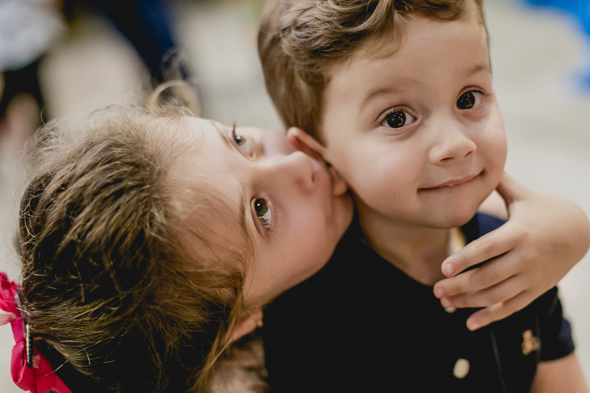 irmã beijando a orelha do irmão