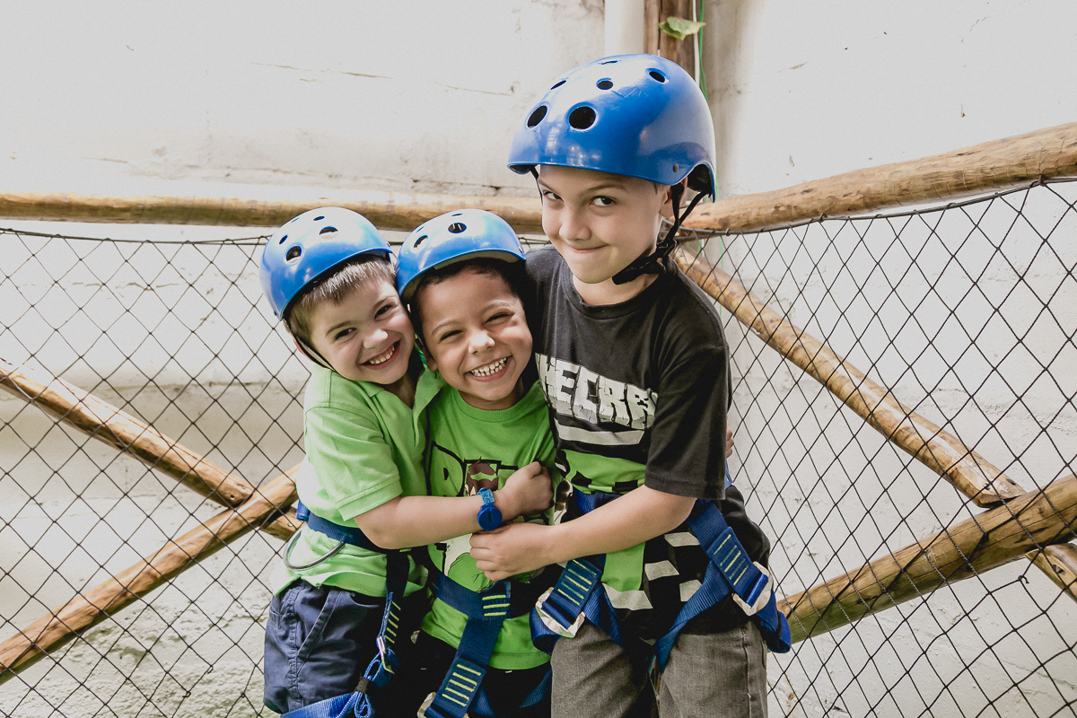 crianças de capacete e dando risada prontas para ir na tirolesa